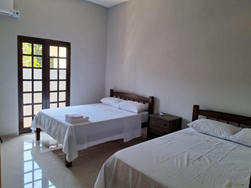 two beds in a room with white walls at Casa Familiar in Paraty