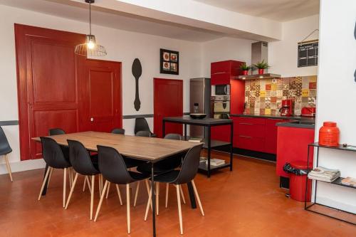 - une cuisine avec des placards rouges, une table et des chaises en bois dans l'établissement Maison de caractère du XVIII siècle, à Saint-Aignan