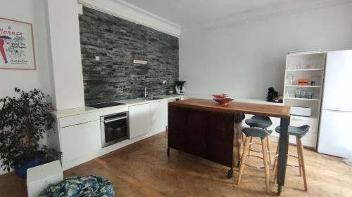 une cuisine avec un îlot en bois et un mur en briques dans l'établissement Spacieux 4 pièces de type bourgeois Art-déco, à Nice