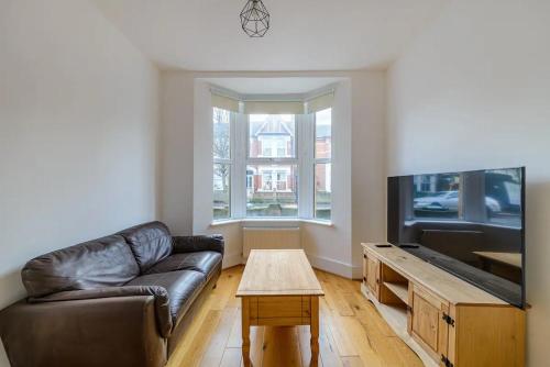 a living room with a leather couch and a flat screen tv at Pass the Keys - Spacious House with a Garden in Stratford, London in London