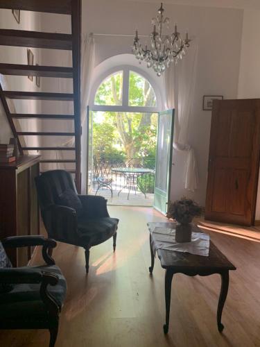 ein Wohnzimmer mit einem Stuhl, einem Tisch und einem Fenster in der Unterkunft Hotel La Fuste in Valensole