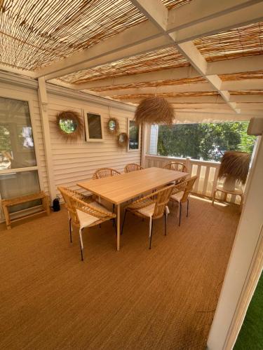 une table et des chaises en bois sur une terrasse dans l'établissement Superbe Bungalow sur la plage de Pampelonne Ramatuelle, à Saint-Tropez