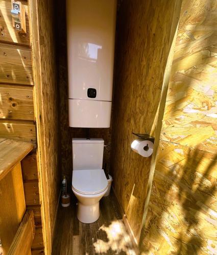 La salle de bains est pourvue de toilettes et d'un mur en bois. dans l'établissement Dodôme Véga Provence étoilée, à Rocbaron
