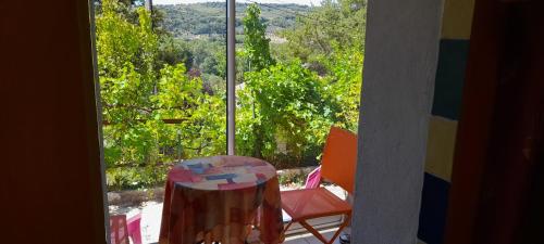 einen Tisch und einen Stuhl vor einem Fenster in der Unterkunft villa les Pins in Mirabel-aux-Baronnies