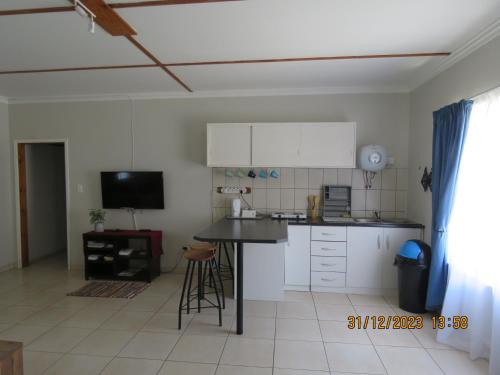 a kitchen with white cabinets and a black counter top at Be My Guest in Swakopmund