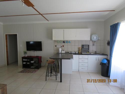 a kitchen with white cabinets and a black counter top at Be My Guest in Swakopmund