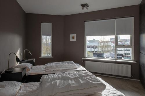 a bedroom with two beds and a large window at Lovely modern 1-bedroom apartment, free parking in Reykjavík
