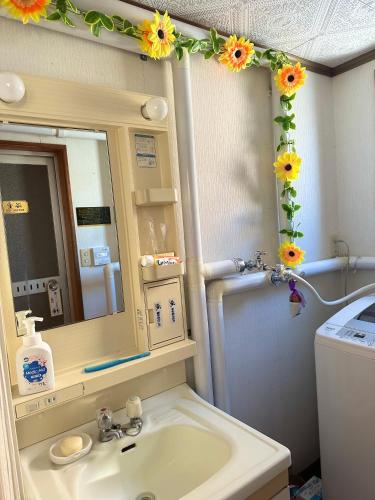 baño con lavabo y espejo con girasoles en 水雲間民宿 en Furano