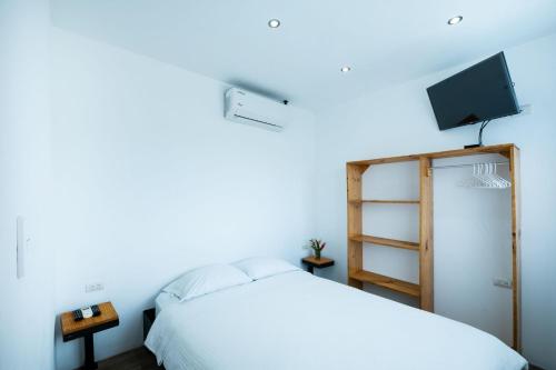 um quarto com uma cama e uma televisão na parede em Hotel Bamboo em Jacó