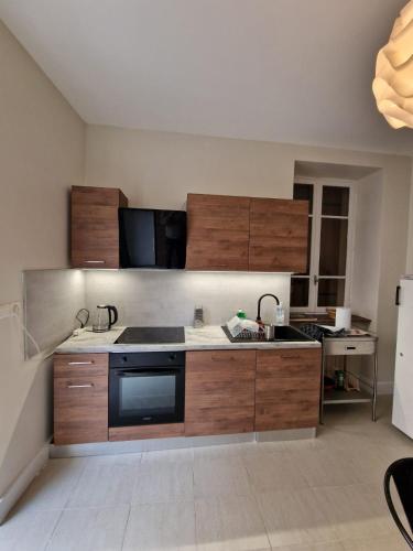 une cuisine avec des armoires en bois, un évier et un réfrigérateur dans l'établissement Grande Maison meublée tout équipé Wifi, Télé, Billard - Demeure de 196 m2 à Tain l'hermitage - 5 Chambres - 17 Couchages, à Tournon-sur-Rhône