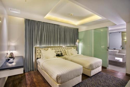 a hotel room with two beds and a bathroom at Grace 21 Smart Hotel in Dhaka
