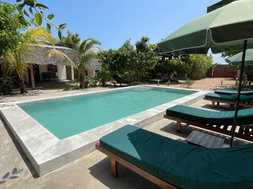 a swimming pool with two lounge chairs and an umbrella at Diana Place in Paje