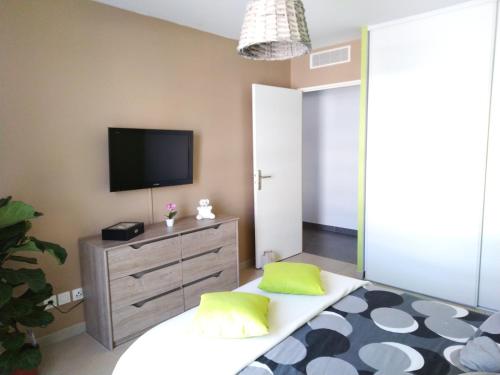 - un salon avec une télévision et un lit avec des oreillers verts dans l'établissement Beau T3 + clim + parking Saint Cyr sur mer, à Saint-Cyr-sur-Mer