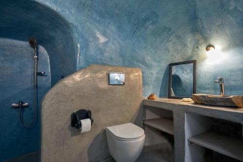 uma casa de banho azul com um WC e um lavatório em Sunlight Cave Agrilia em Therasia