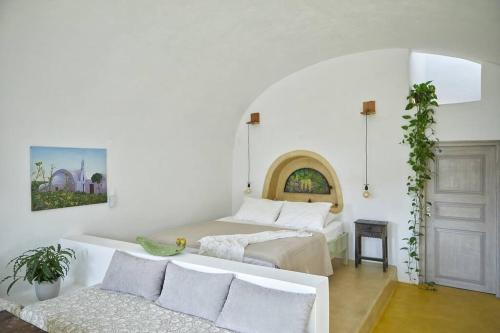 um quarto branco com 2 camas e um sofá em Sunlight Cave Agrilia em Therasia