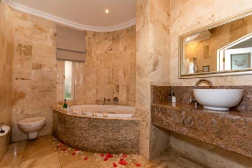 a bathroom with a tub and a toilet and a sink at Walkersons Hotel & Spa in Dullstroom