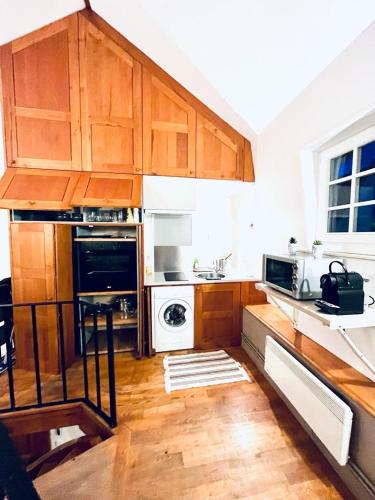 une cuisine avec des armoires en bois et un four à plaques de cuisson dans l'établissement Tropical Duplex in Senlis, à Senlis