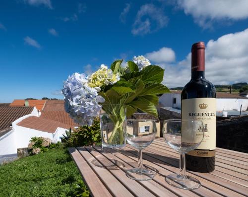 a bottle of wine and two glasses and a vase of flowers at Casa da Salga in Nordeste