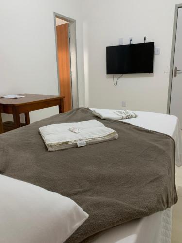 a hotel room with two beds and a flat screen tv at Pousada Salomão in Teixeira de Freitas