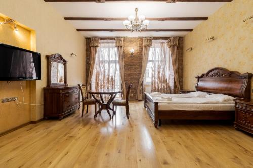 a bedroom with a bed and a table and a tv at Апартаменти на Площі Ринок, 20 in Lviv