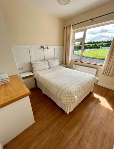 a bedroom with a large bed and a window at Breenville Farm House in Tralee