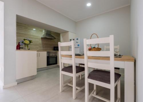 a kitchen with white chairs and a wooden counter top at Casa da Salga in Nordeste