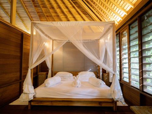a white bed with a canopy in a room at De Ubud Villas & Spa in Ubud