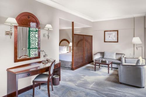 a hotel room with a desk and a bedroom at Madinah Hilton Hotel in Al Madinah