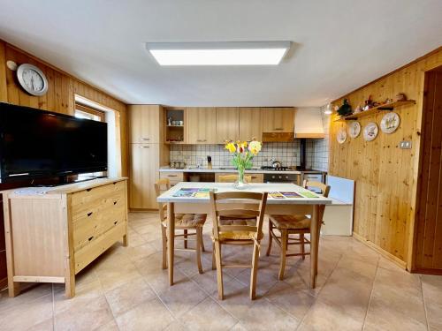 a kitchen with a table with chairs and a tv at Maso Patrizia - Rifugio caldo tra le vette in Pieve Tesino
