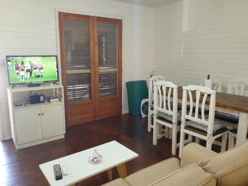 a living room with a television and a table and chairs at Doha, paraíso mar y bosque in Rincón de los Oliveras