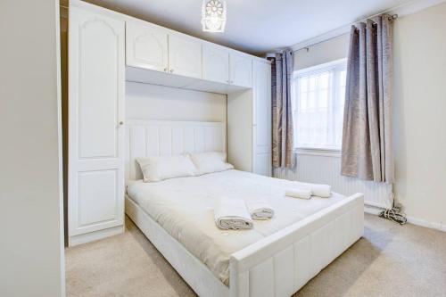 um quarto com uma cama branca com duas toalhas em Pass the Keys Spacious 4-Bedroom Home in Benfleet em Battlesbridge