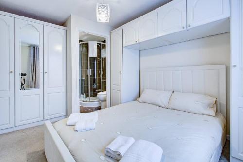1 dormitorio blanco con 1 cama grande y baño en Pass the Keys Spacious 4-Bedroom Home in Benfleet, en Battlesbridge