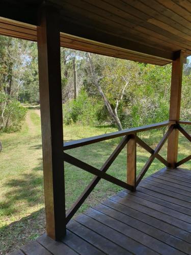 a wooden porch with a view of a field at Doha, paraíso mar y bosque in Rincón de los Oliveras