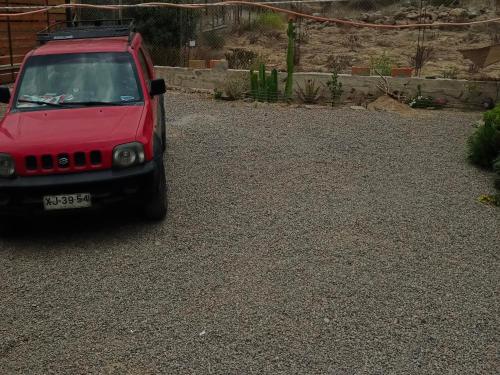 a red jeep parked in a gravel driveway at Cabaña Totoralillo in Coquimbo