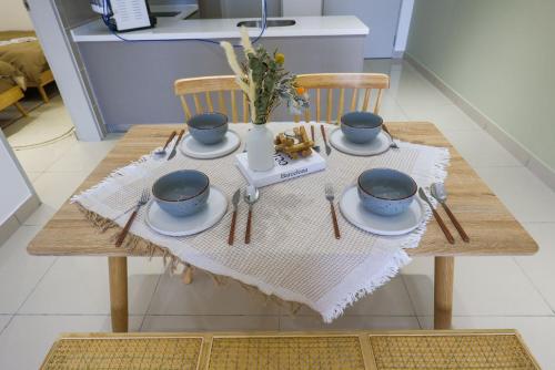 a wooden table with plates and cups on it at 10 min to My town family unit By Nexx Field in Kuala Lumpur