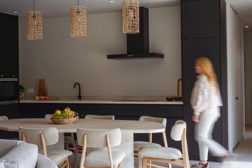 a woman walking in a kitchen with a table and chairs at VAKANTIEDOMEIN DOUVE in Heuvelland