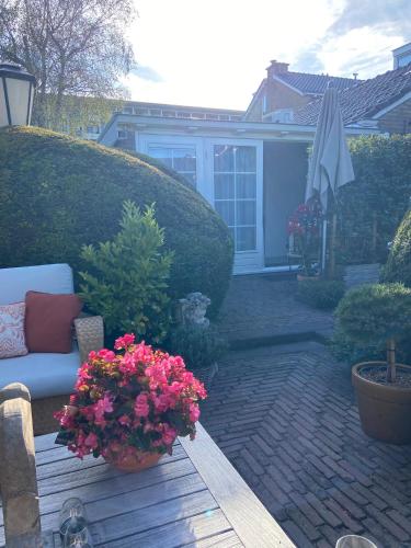 a patio with flowers and a couch and an umbrella at B&B Ereprijs in The Hague