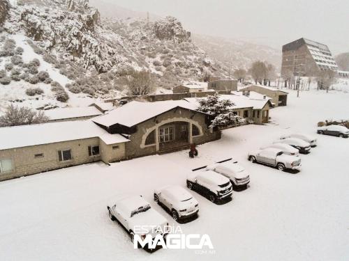 un grupo de autos estacionados en un estacionamiento cubierto de nieve en Hotel Termas Lahuen-Có en Los Molles