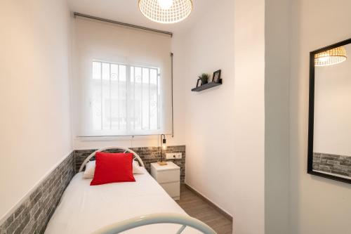 um quarto com uma cama com uma almofada vermelha em Beach Apartment, next to the sea em Premiá de Mar