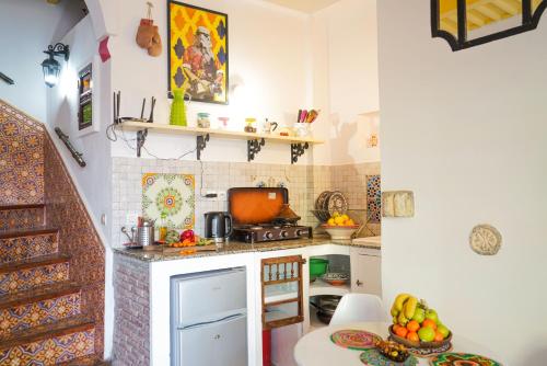 a kitchen with a stove and a table with a bowl of fruit at Dar 91 Essaouira in Essaouira