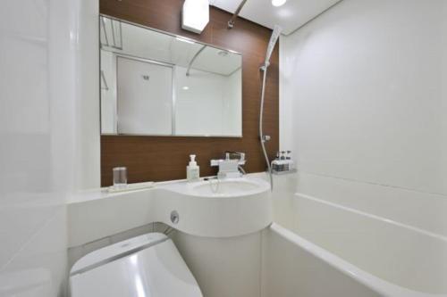 a white bathroom with a sink and a mirror at Hotel NCB in Osaka