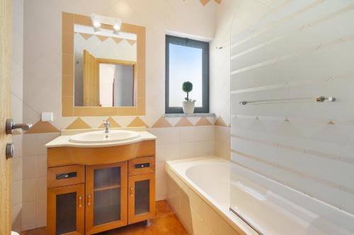 bagno con lavandino, vasca e specchio di Vilita Oasis Family Apartment a Pêra