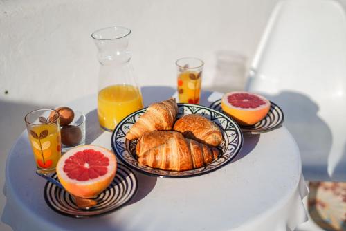 a table topped with plates of croissants and oranges at Dar 91 Essaouira in Essaouira