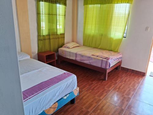 2 Betten in einem Zimmer mit grünen Vorhängen in der Unterkunft Dylan Beach in Zorritos