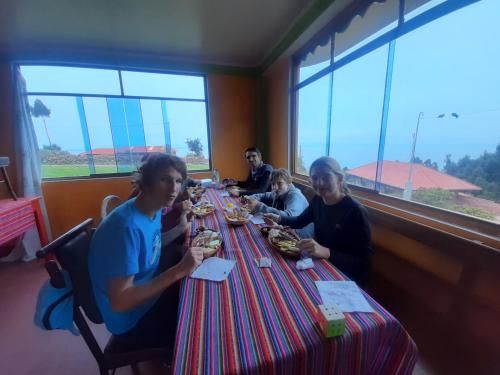 grupa ludzi siedzących przy stole jedzących jedzenie w obiekcie Taquile Inti Raymi Lodge w mieście Huillanopampa