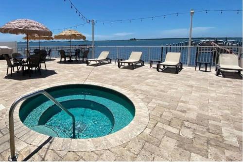 a swimming pool with chairs and tables and the ocean at Condo in Waterfront Resort with Balcony Close to Beaches Free Bikes in Dunedin