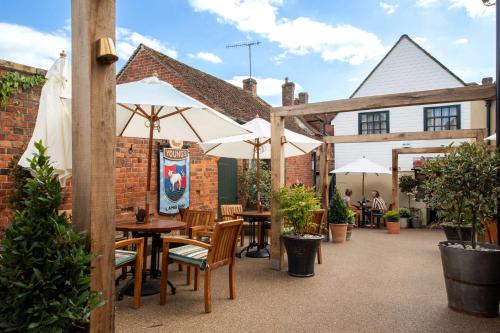 un patio al aire libre con mesas y sombrillas en The Lamb Inn, en Hindon