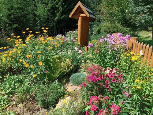 a garden with colorful flowers and a wooden fence at Srub Javorná - apartmány Šumava in Javorná