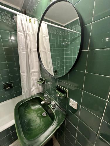 La salle de bains est pourvue d'un lavabo vert et d'un miroir. dans l'établissement Amplio Departamento en Zona Gastronómica a una cuadra de la Playa, à Mar del Plata