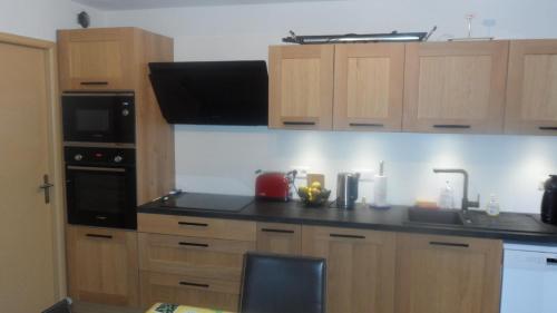 une cuisine avec des armoires en bois et un comptoir noir dans l'établissement Villa 47 Hameau des Greens, à Sainte-Maxime